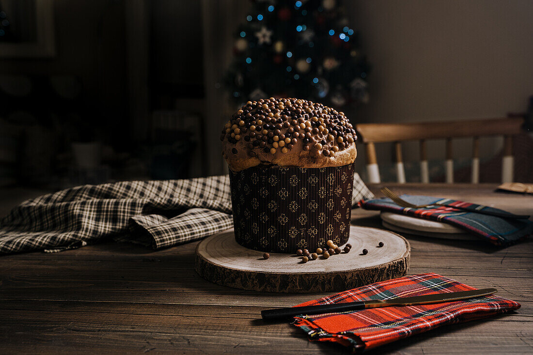 Süßer hausgemachter Panettone auf rundem Holzständer in der Nähe eines Messers zur Weihnachtsfeier