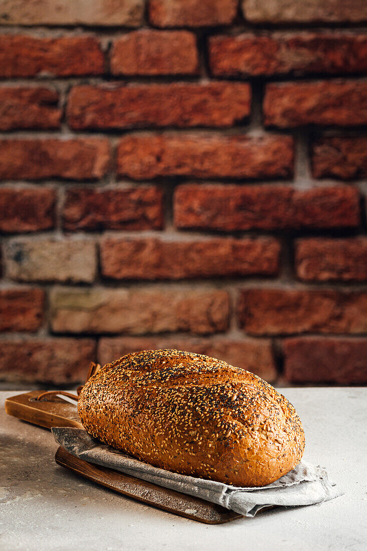 Leckeres Vollkornbrot auf Schneidebrett auf Tisch