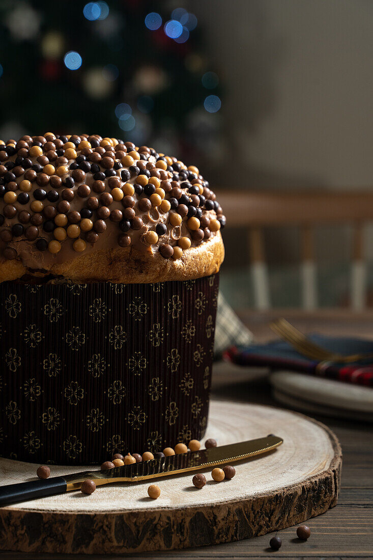 Süßer hausgemachter Panettone auf rundem Holzständer in der Nähe eines Messers zur Weihnachtsfeier