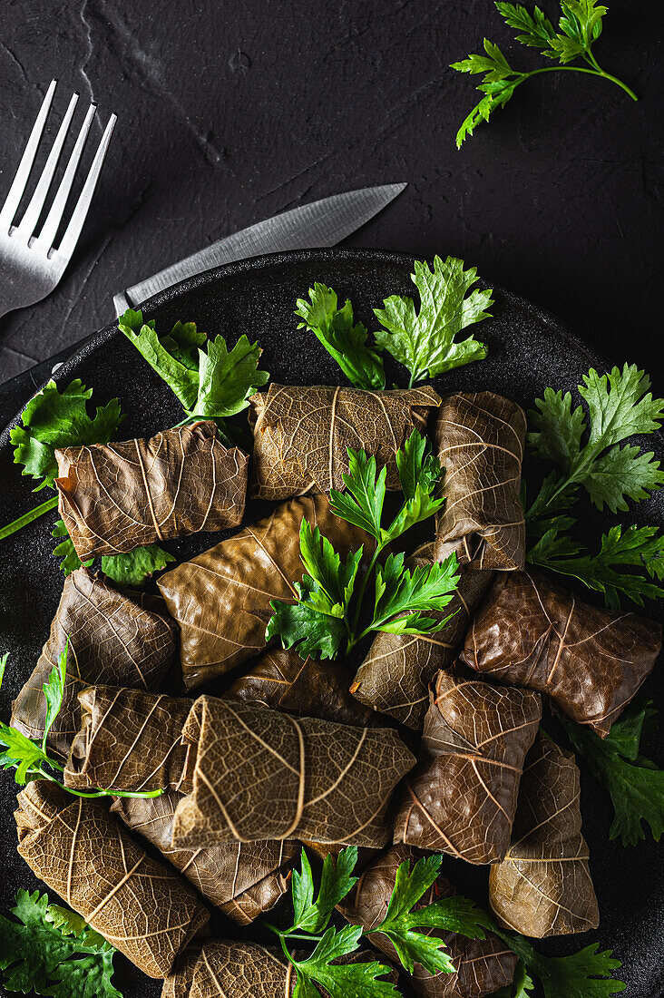 From above of palatable sarma with parsley and fork on dark background