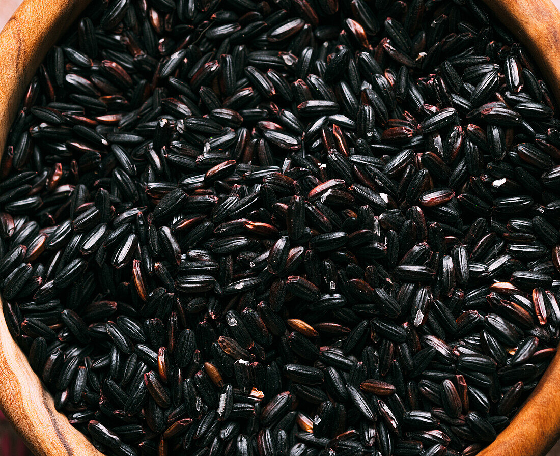 Nahaufnahme von oben einer Holzschüssel mit einem Haufen schwarzem Naturreis zum Mittagessen