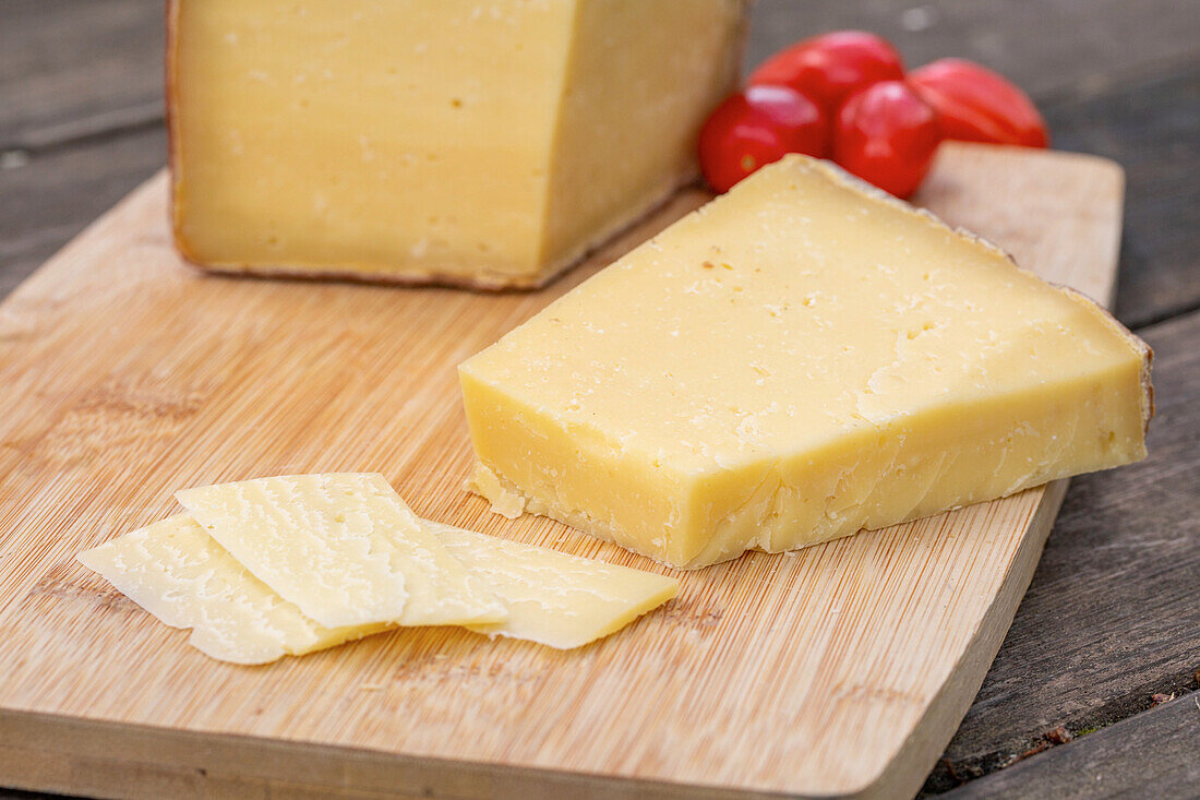 Köstlicher italienischer Pecorino toscano-Käse mit Kirschtomaten auf einem Schneidebrett auf einem Holztisch