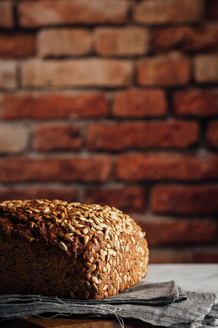 Leckeres Vollkornbrot auf Schneidebrett auf Tisch