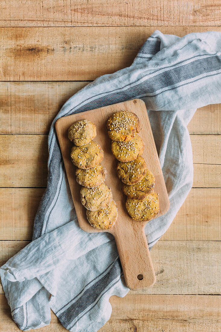 Draufsicht auf ein Schneidebrett mit leckeren Süßkartoffel-Falafel auf einer Stoffserviette auf einem Holztisch