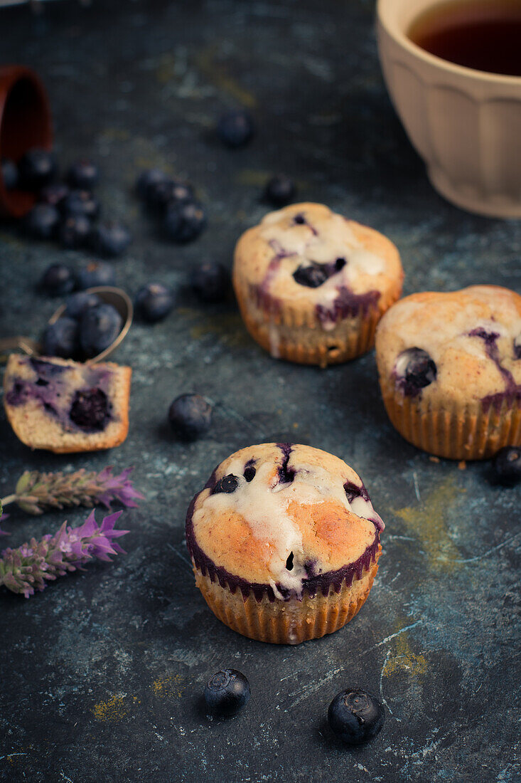 Hohe Winkel von süßen hausgemachten Muffins mit Sahne und Blaubeeren in der Nähe von Löffel Minzblatt und Blume und bereit für Dessert