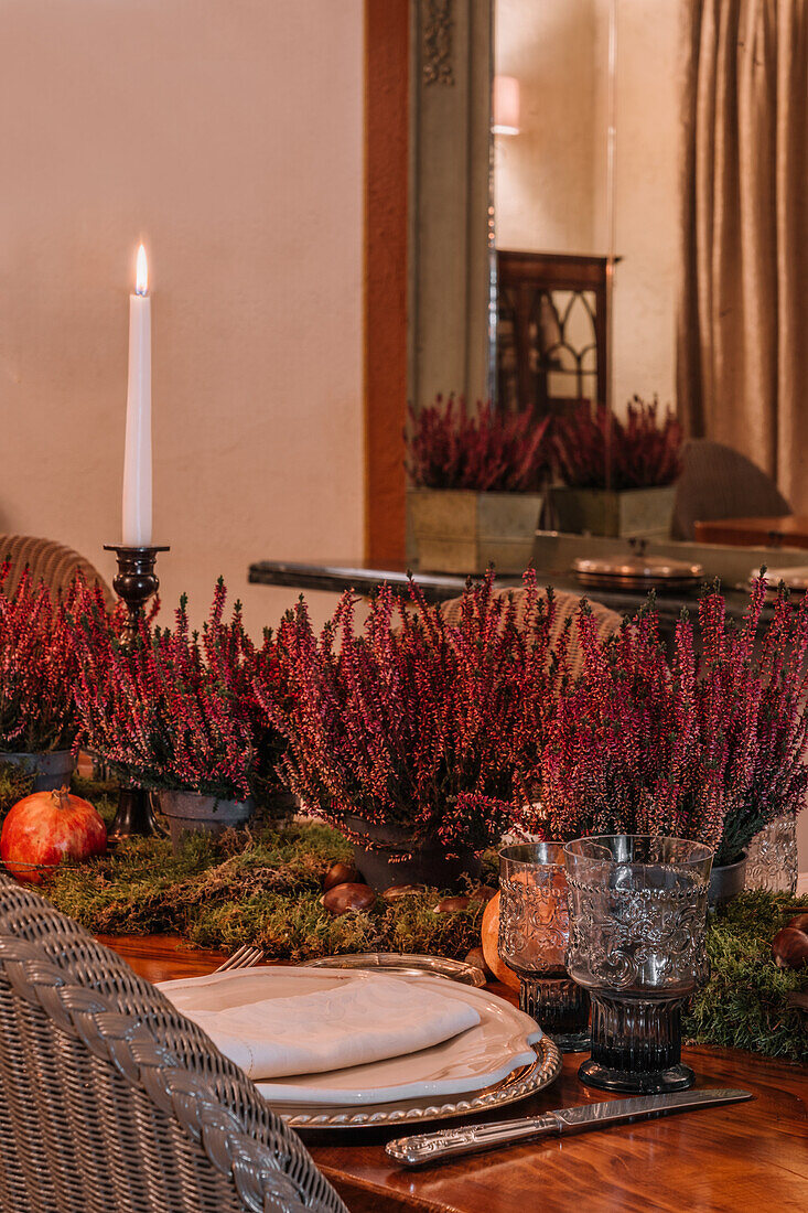 Interieur eines Esszimmers mit Holztisch, Besteck und mit Blumen dekorierten Tellern für das Abendessen