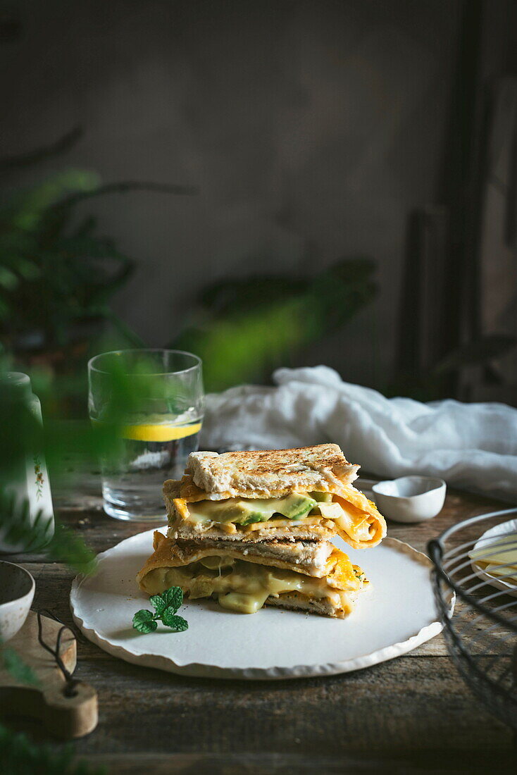 Avocado, Käse, Omelett-Sandwich auf Keramikteller auf Holztisch serviert