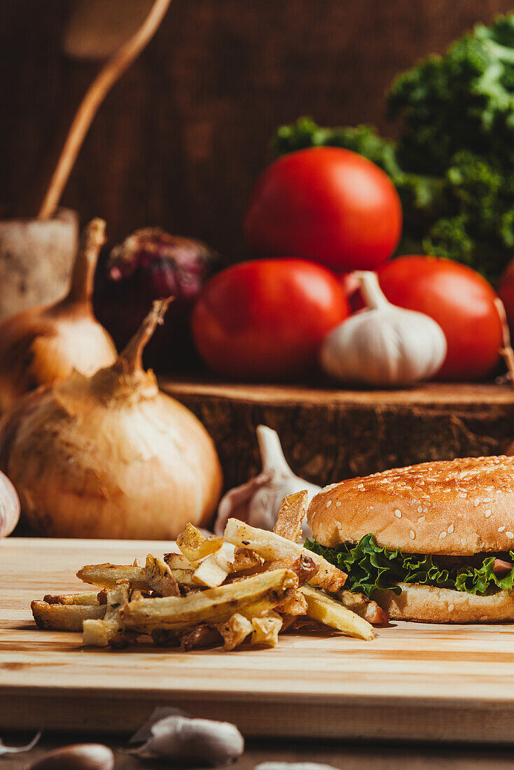 Appetitliche Hamburger mit Gemüse auf Holzbrett mit Pommes frites in Küche