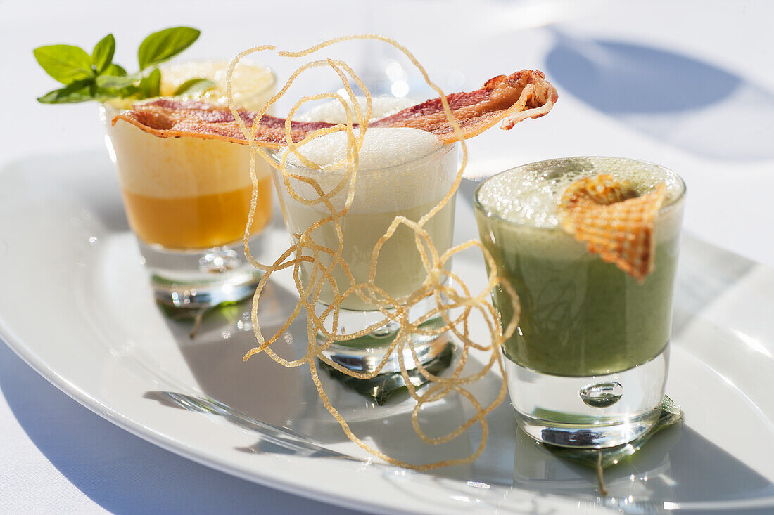 Potato soup, spinach soup and carrot soup in a glass