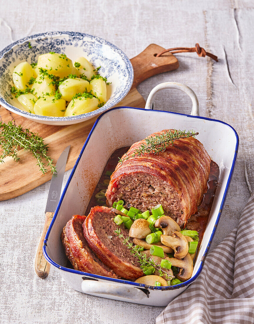 Meatloaf wrapped in bacon with mushrooms and potatoes