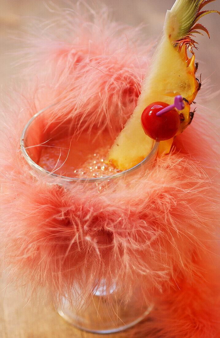 Pink cocktail with pineapple and cherry