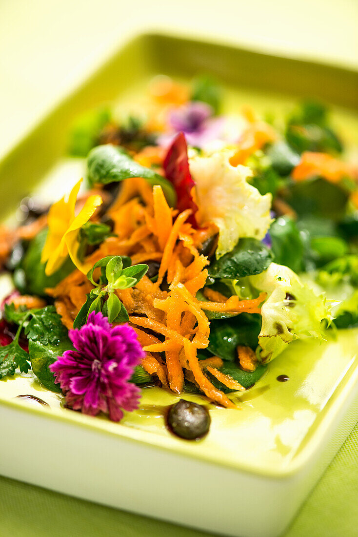 Carrot salad with roasted pumpkin seeds, spinach and flowers