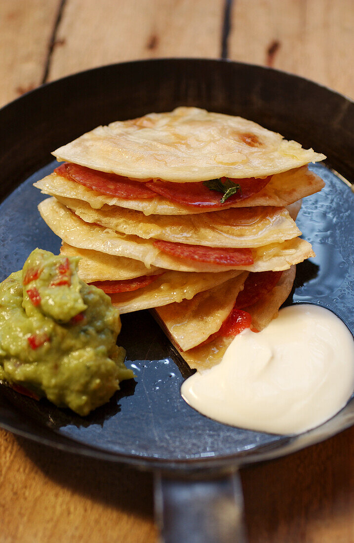 Quesadilla with salami, guacamole and sour cream