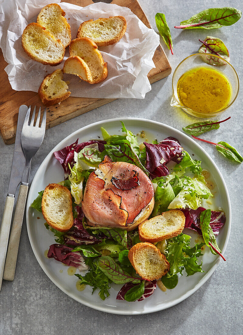 Baked camembert with ham, leaf salad and toasted bread