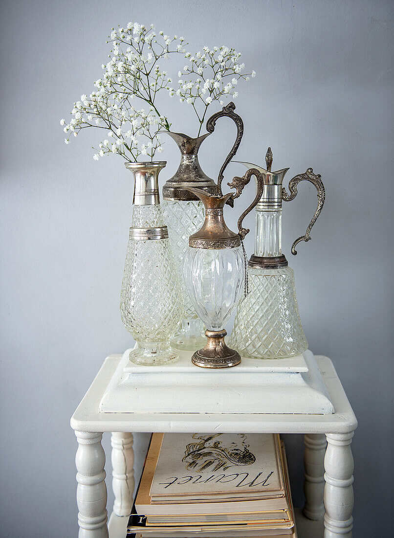 Antique crystal carafes with silver decorations and trailing herbs on a wooden table