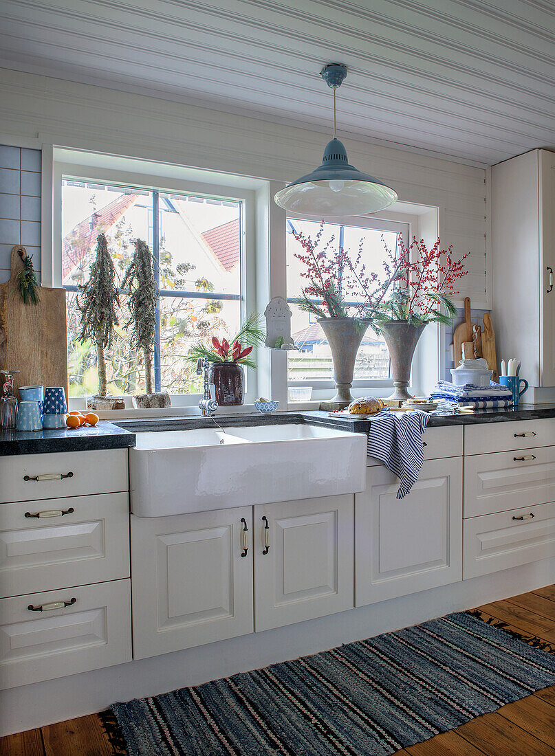 Bright country kitchen with white ceramic sink and decorative vases in front of the window