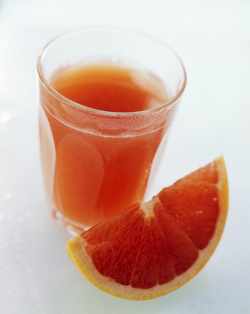 A Glass of Red Grapefruit Juice with Grapefruit Wedge