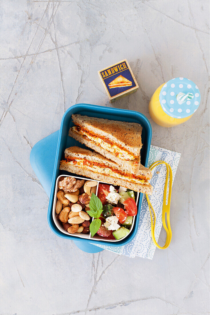 Bento box with sandwich, salad and nuts