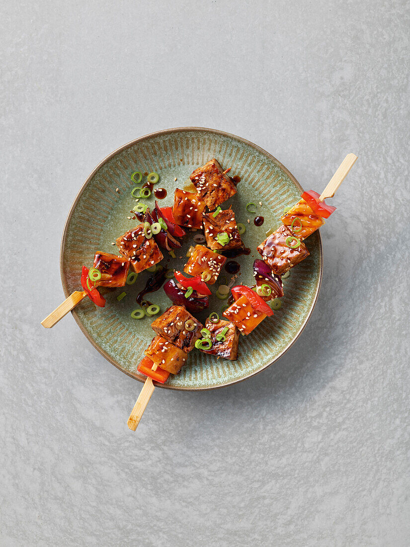 Teriyaki tofu vegetable skewers with spring onions and sesame seeds