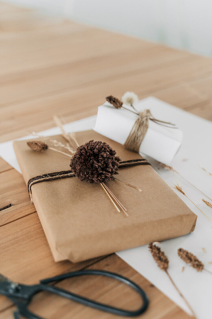 Wrapped gifts with natural materials and pompoms on a wooden table