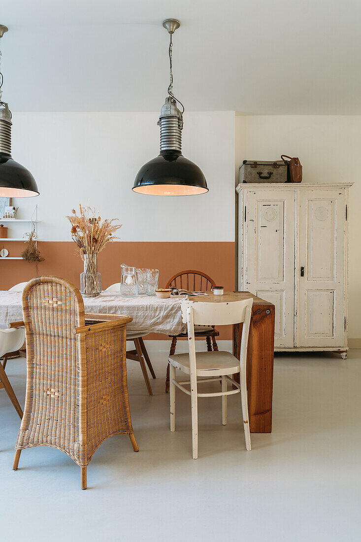 Dining room with vintage charm: rattan furniture, wooden table and antique cupboard