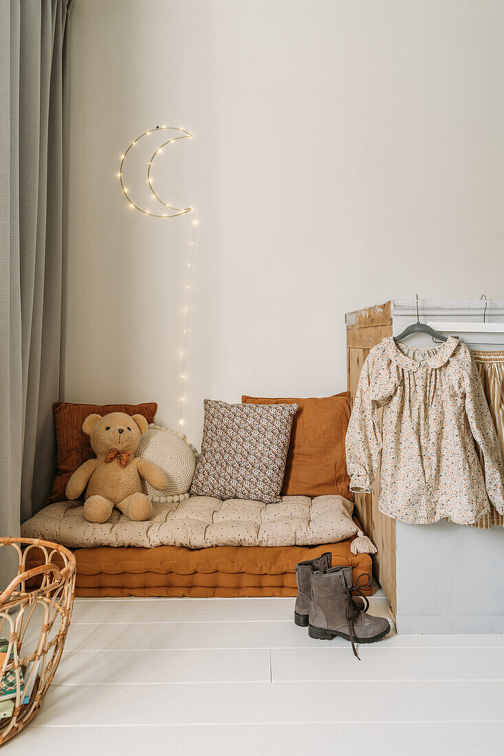 Cosy children's room corner with cushions and fairy lights in the shape of the moon