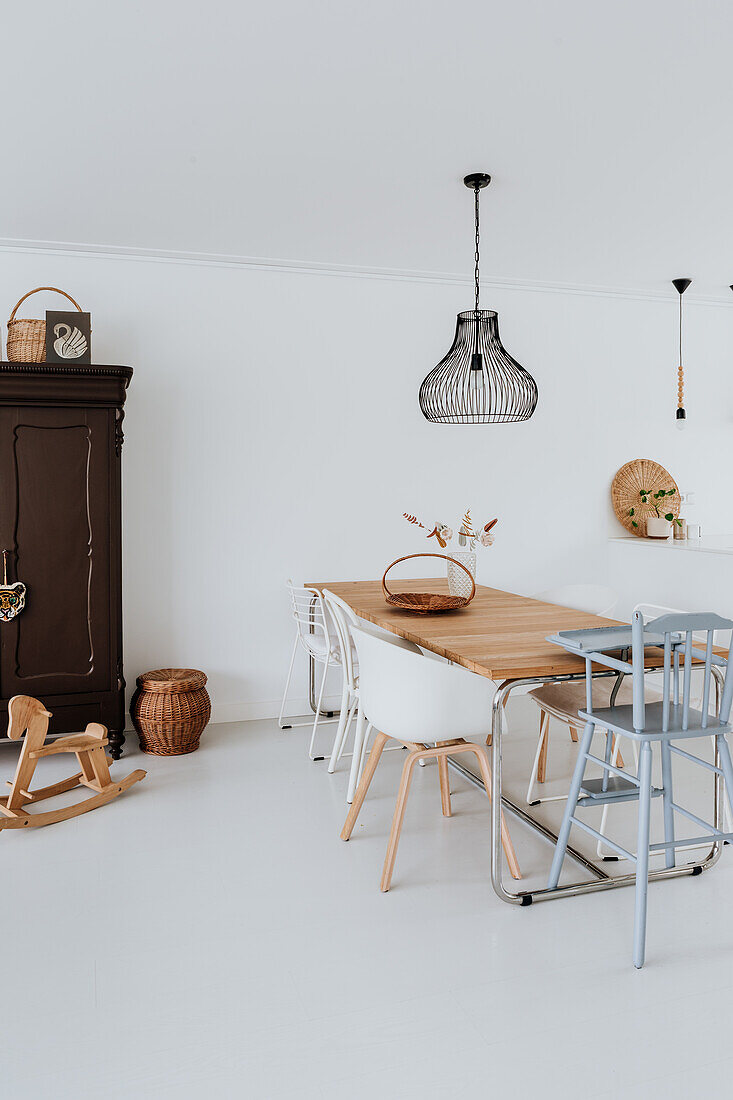 Dining area with wooden table, various chairs and black pendant light