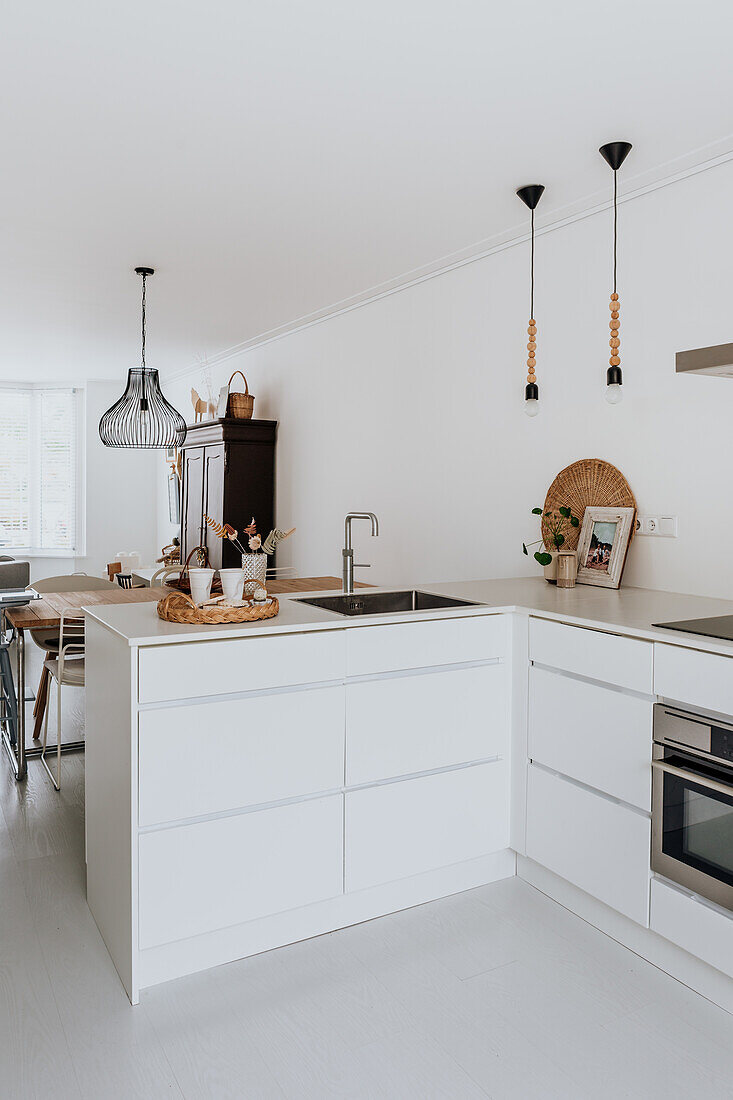 Minimalist kitchen with white cabinets and pendant lights