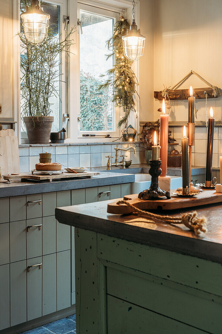 Cosy kitchen with candles, concrete worktop and green cupboards