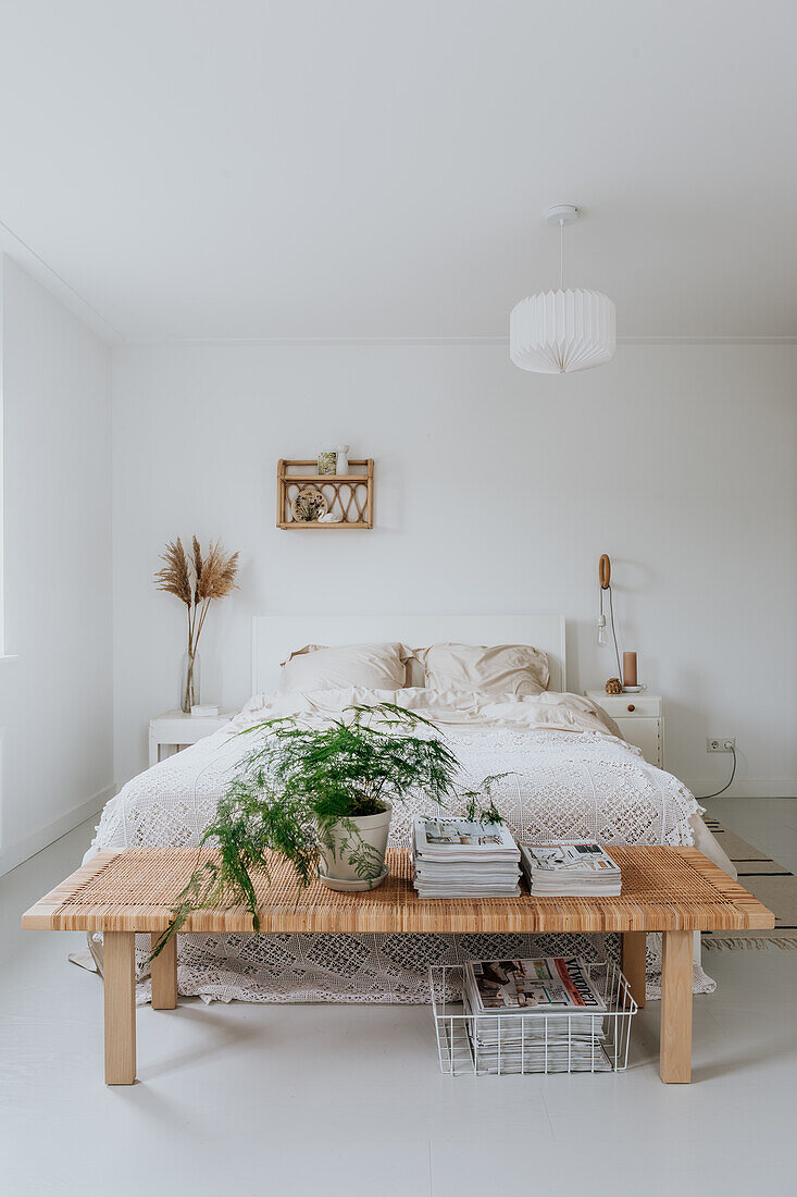 Bright bedroom with double bed, wall shelf and plant on bed bench