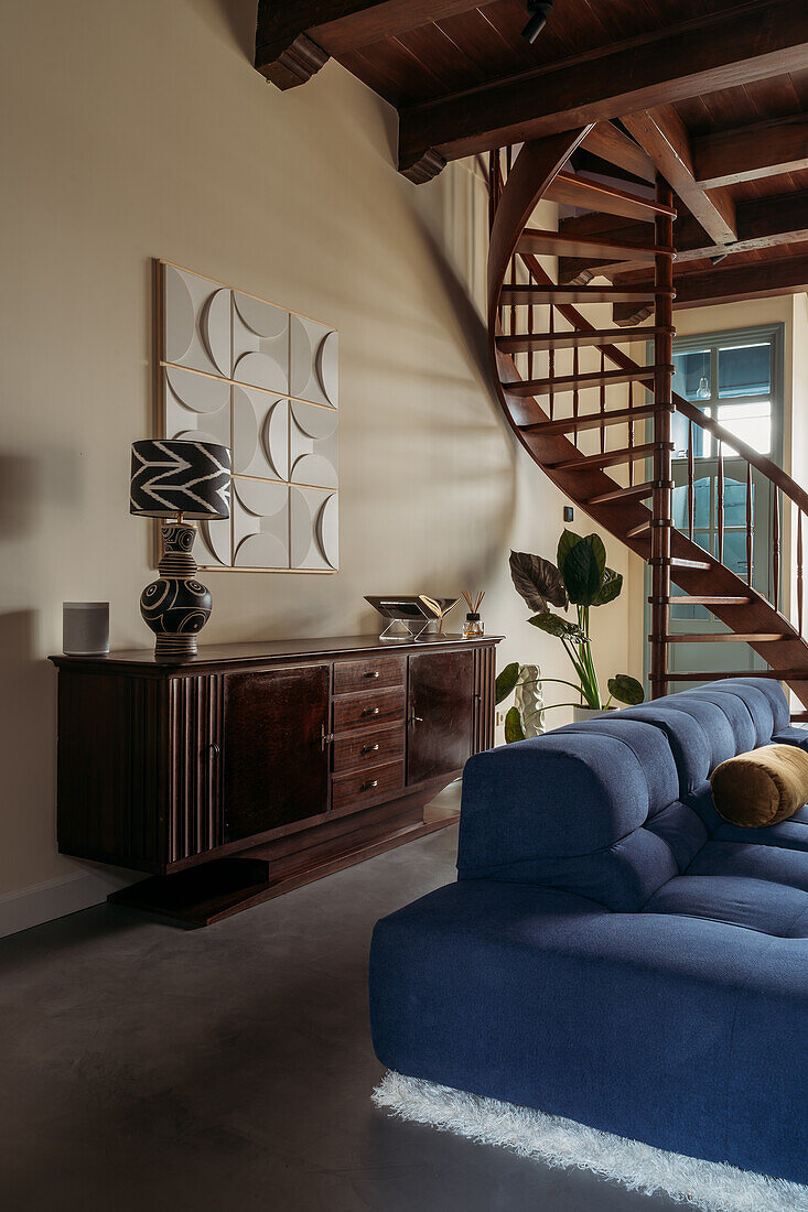 Wooden staircase in living room with blue sofa and wooden sideboard