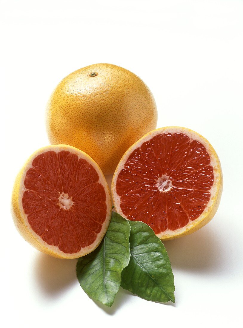 Two Red Grapefruits, One Whole and One Halved, with Leaves