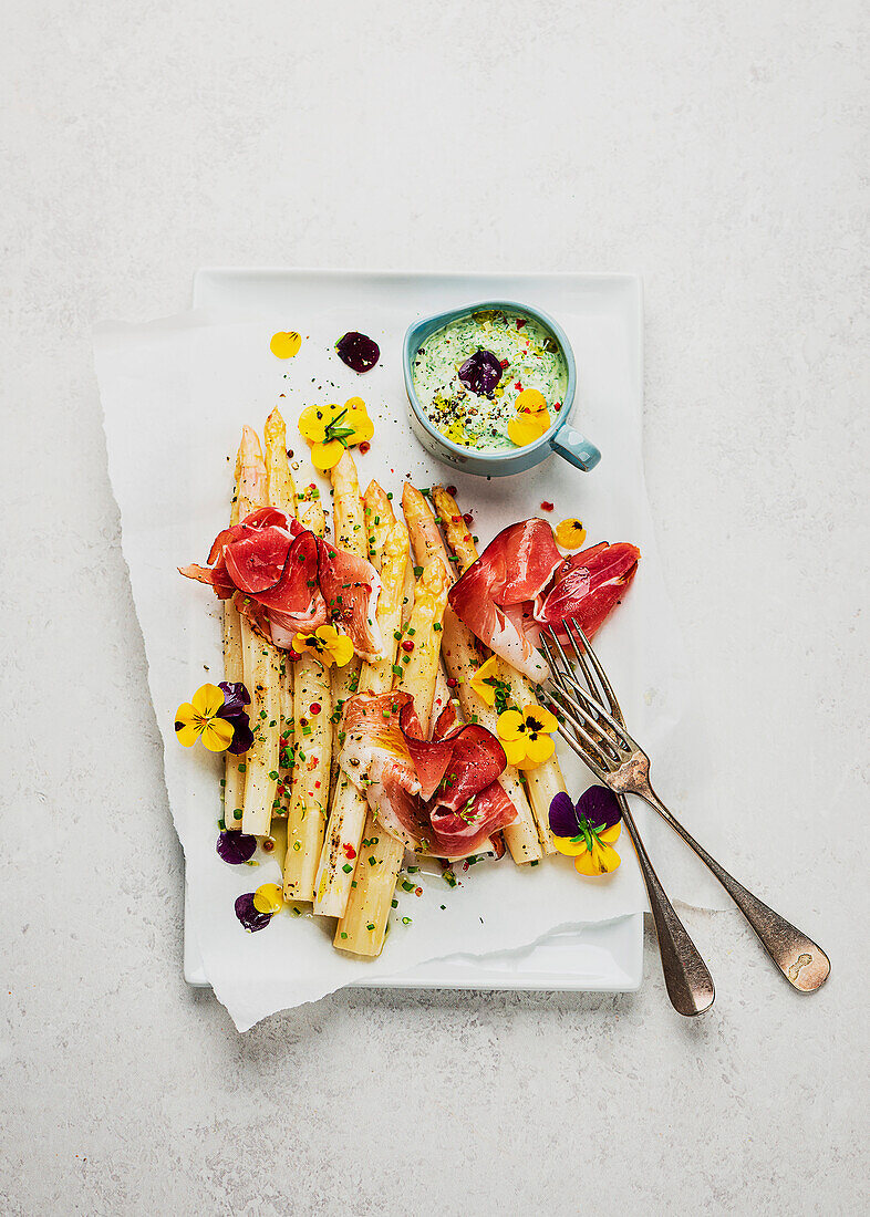 Asparagus from the tray with green sauce and ham