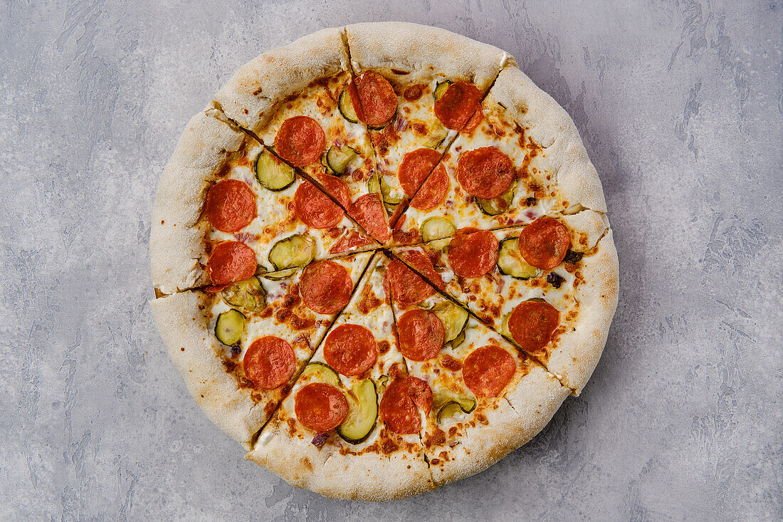 Pizza mit scharfer Salami, Gurke und Käserand