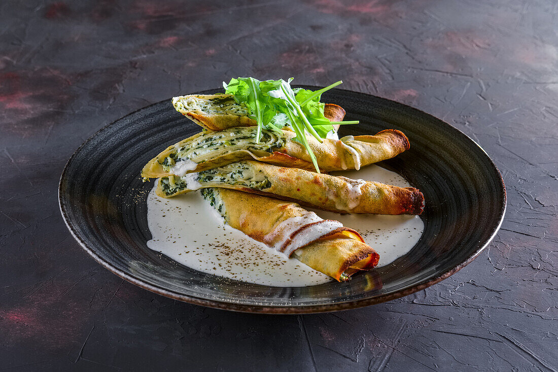 Stuffed pancakes with cheese and rocket sauce