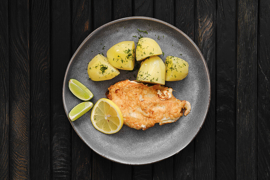 Fried cod in cheese breading with boiled potatoes and lemon