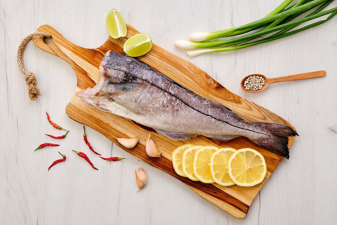 Raw haddock on a wooden board with citrus fruits and garlic