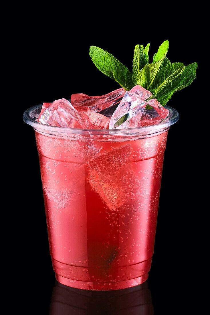 Strawberry and mint cocktail in a plastic cup with ice cubes