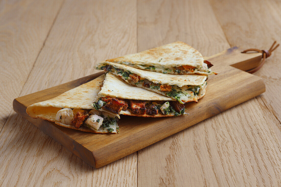 Quesadilla with chicken, vegetables and cheese on a wooden board