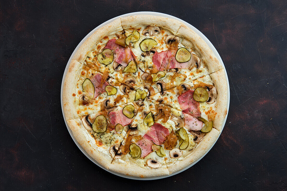 Pizza with bacon, mushrooms, gherkins and caramelised onions