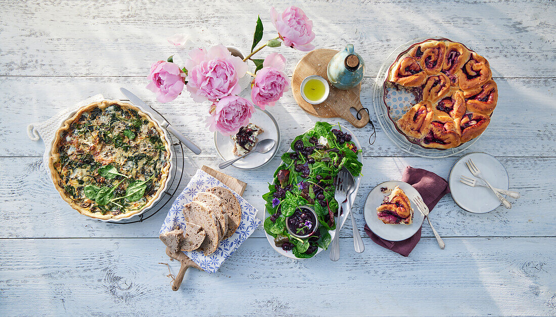 Gedeckter Tisch mit Spinatquiche, Salat und Hefegebäck