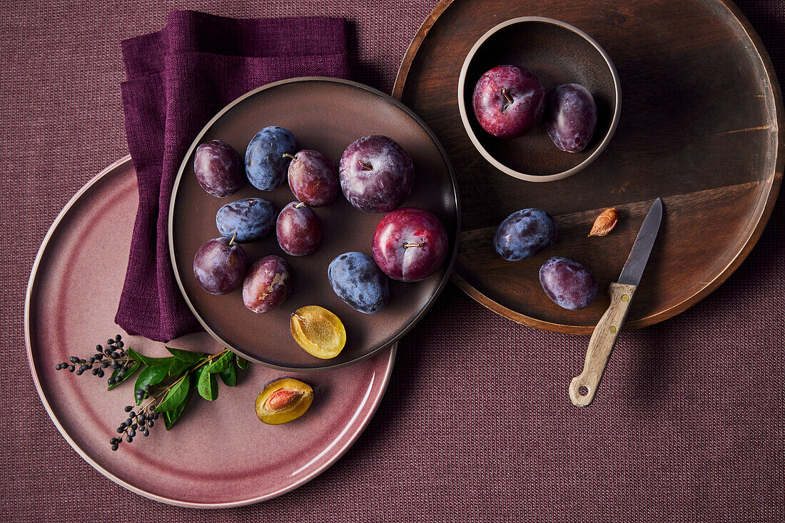 Sliced and whole plums on plates and bowls