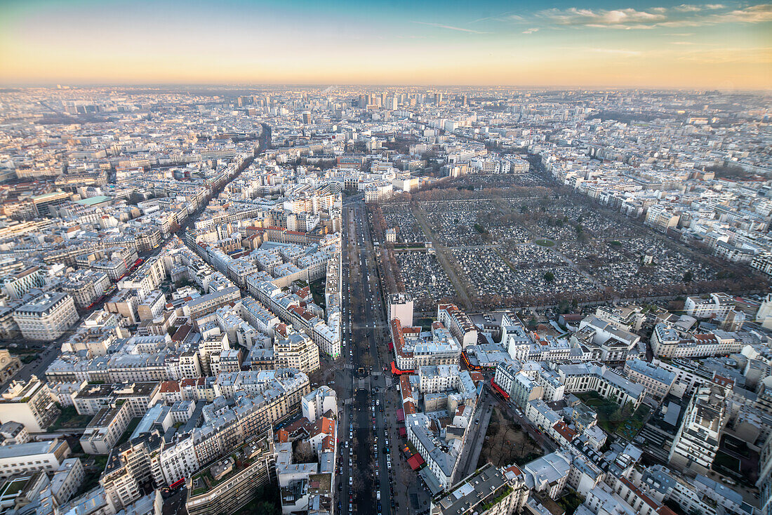 Aerial view of Montparnasse Cemetery among Parisian streets at dusk.