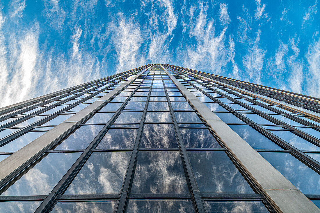 Looking up at the towering Montparnasse Tower against a backdrop of wispy clouds.