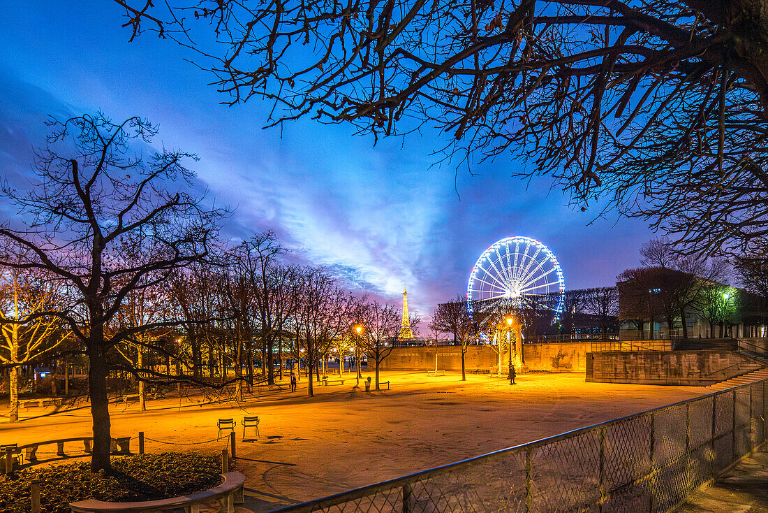 Die Abenddämmerung legt sich über die Tuilerien-Gärten und zeigt das strahlende Riesenrad und den weit entfernten Eiffelturm.