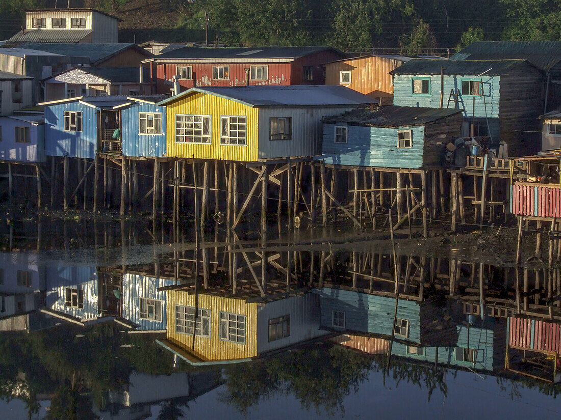 Colorful palafitos or fishermen's stilt houses reflected in an inlet at sunrise in Castro on Chiloe Island, Chile.