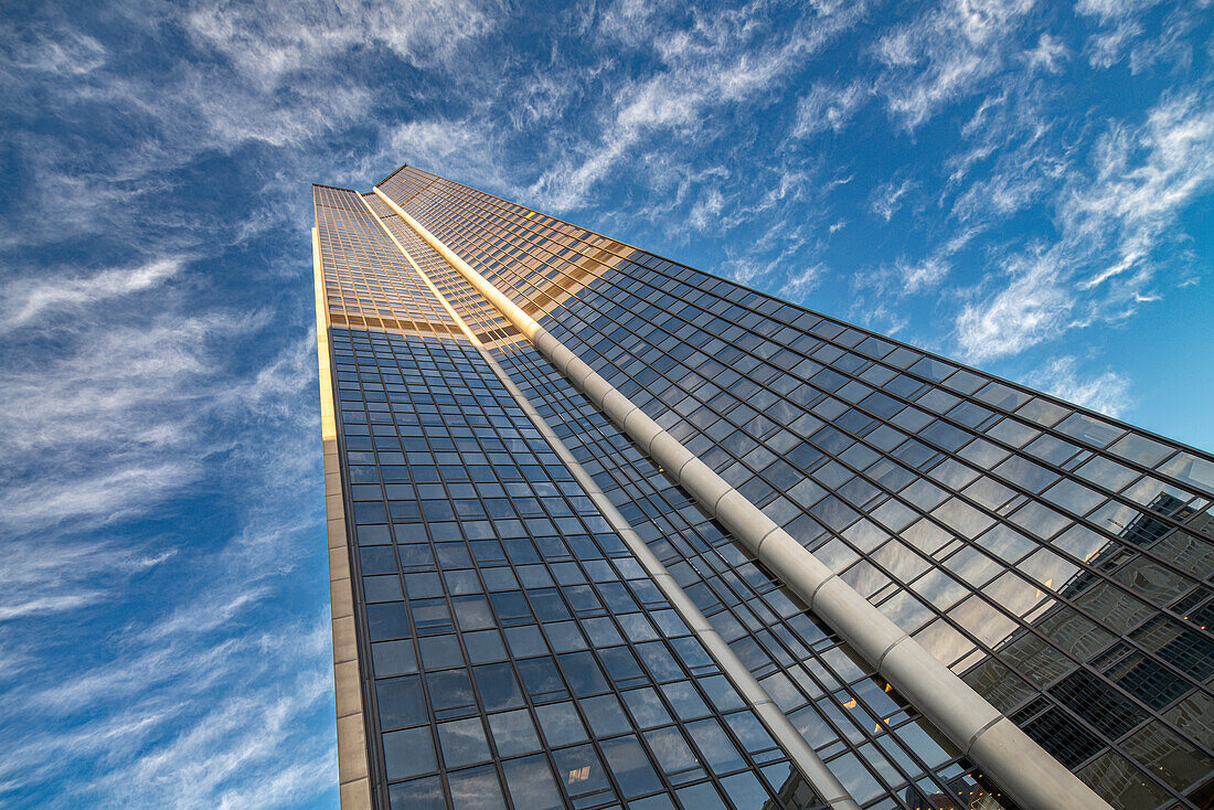 Looking up at the towering Montparnasse Tower against a backdrop of wispy clouds.