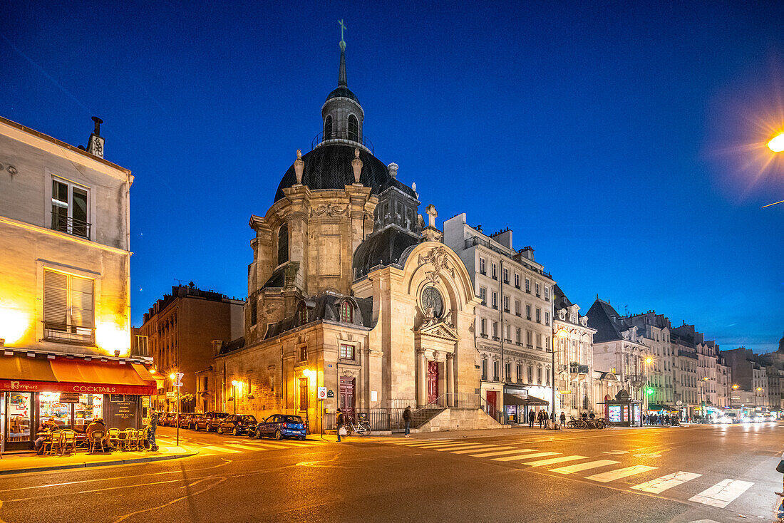 Dusk settles over Eglise Protestante du Marais with city lights illuminating the street.