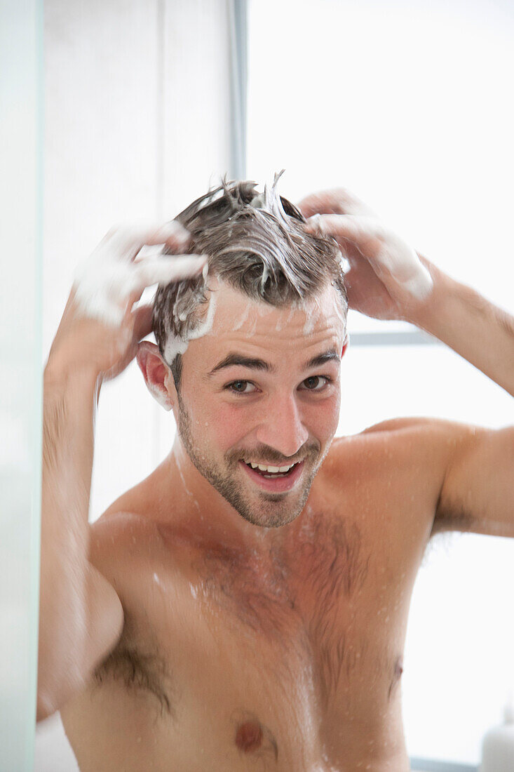 Lächelnder Mann beim Haarewaschen in der Dusche