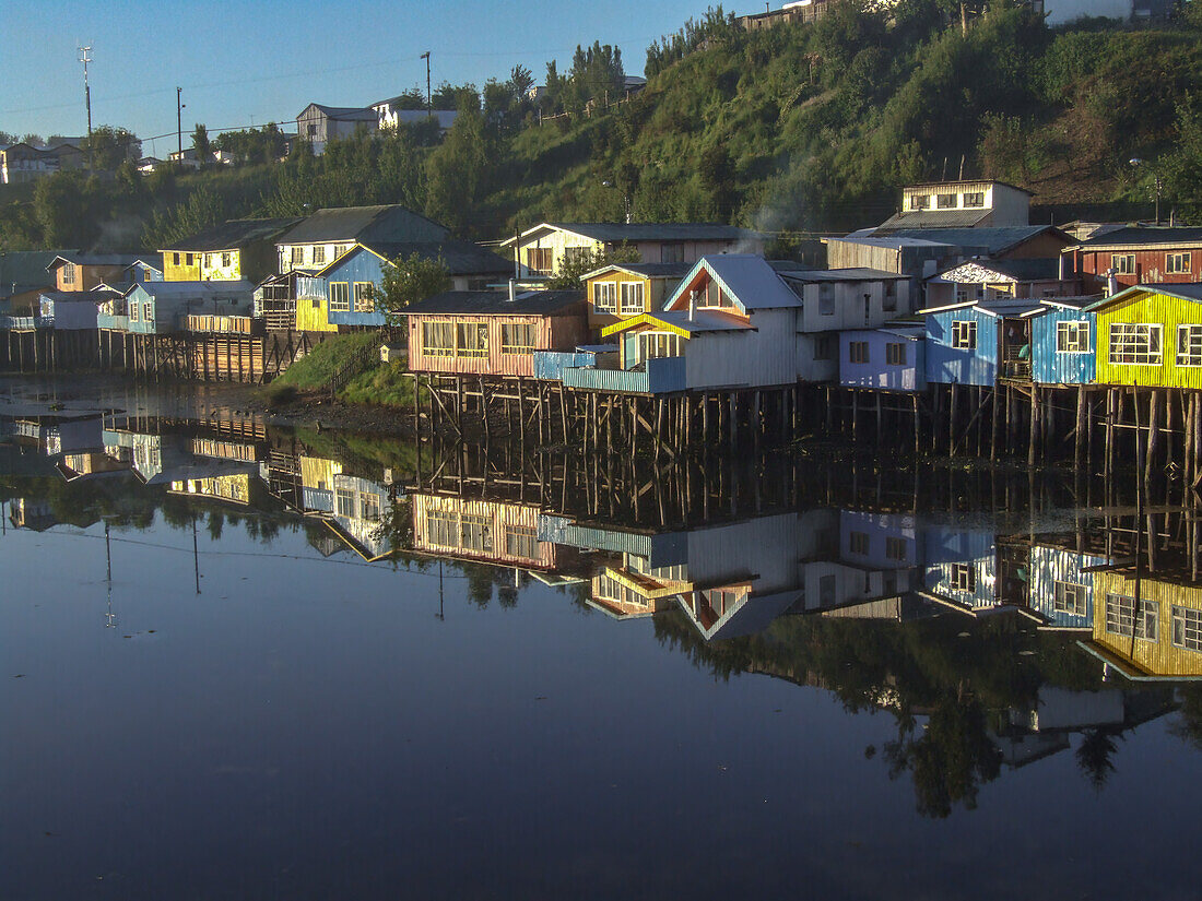 Colorful palafitos or fishermen's stilt houses reflected in an inlet at sunrise in Castro on Chiloe Island, Chile.